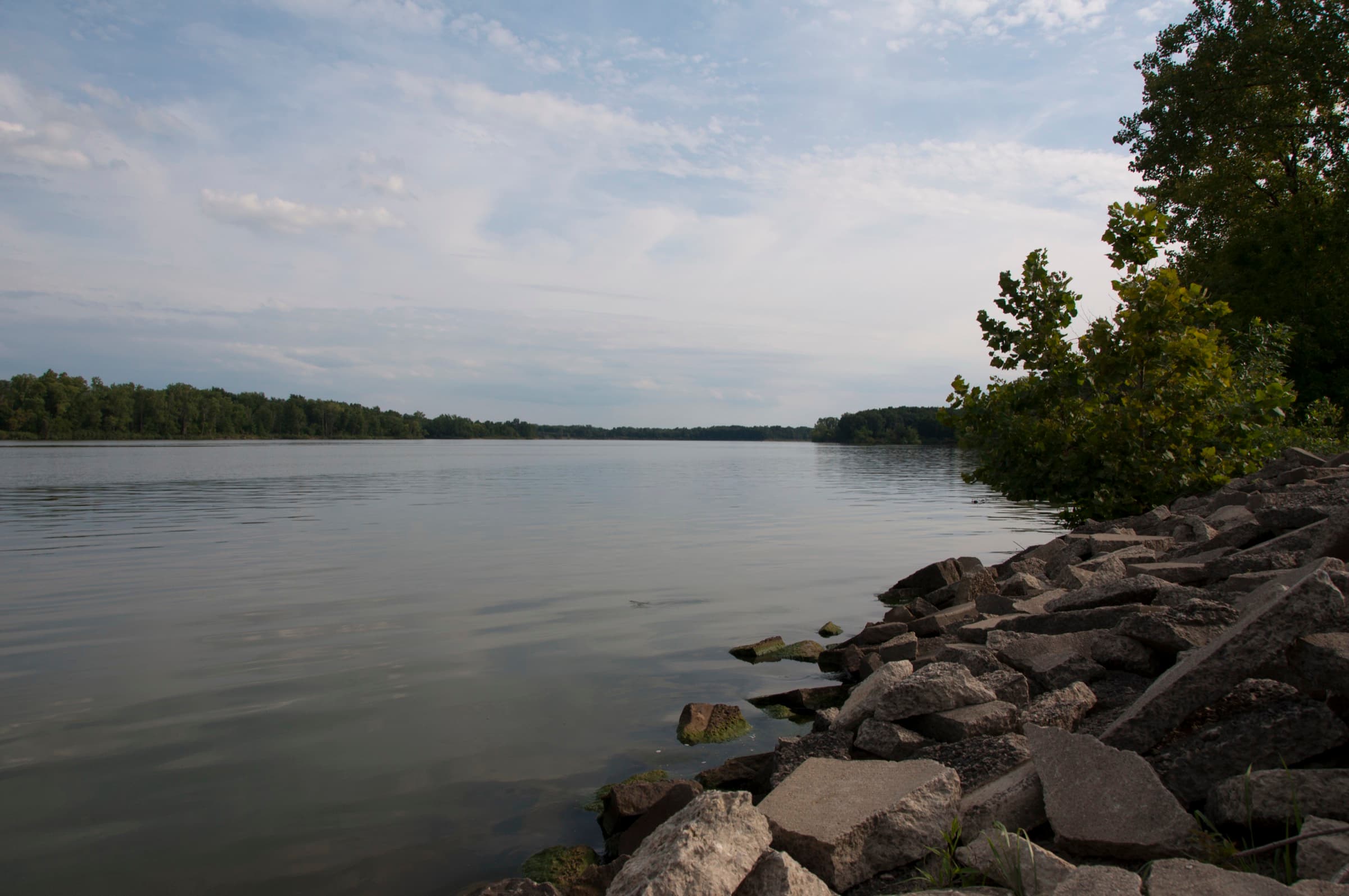 Rocky shoreline and calm open water of Delaware Lake at Delaware State Park on a summer afternoon