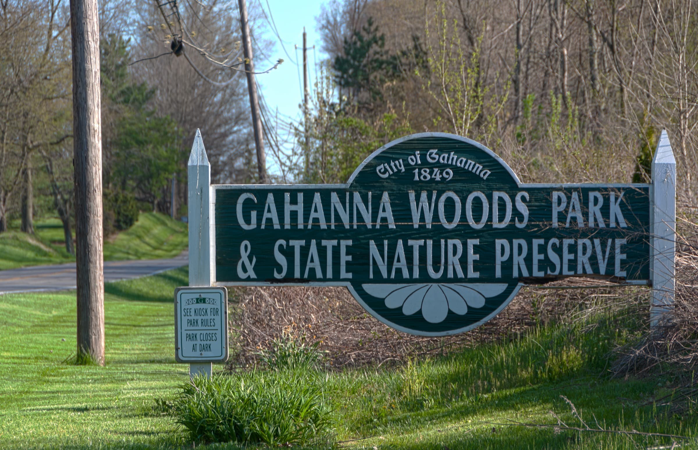 The wooden entrance sign for Gahanna Woods Park and State Nature Preserve surrounded by spring greenery