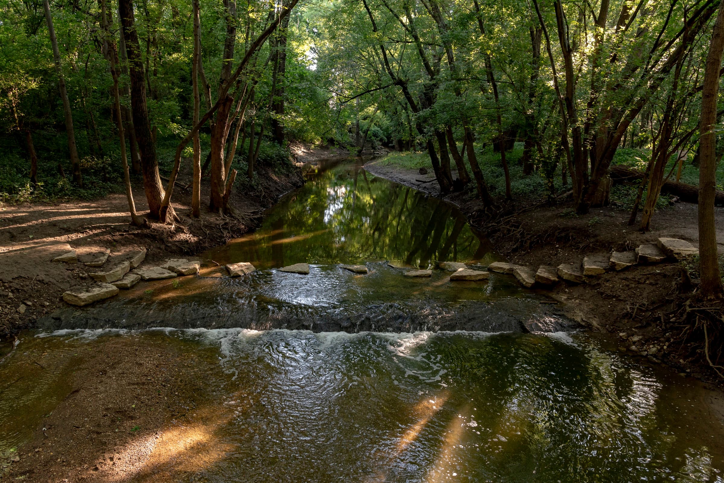 Stepping stones across Grant Run creek under the trees at Scioto Grove Metro Park in Grove City, Ohio