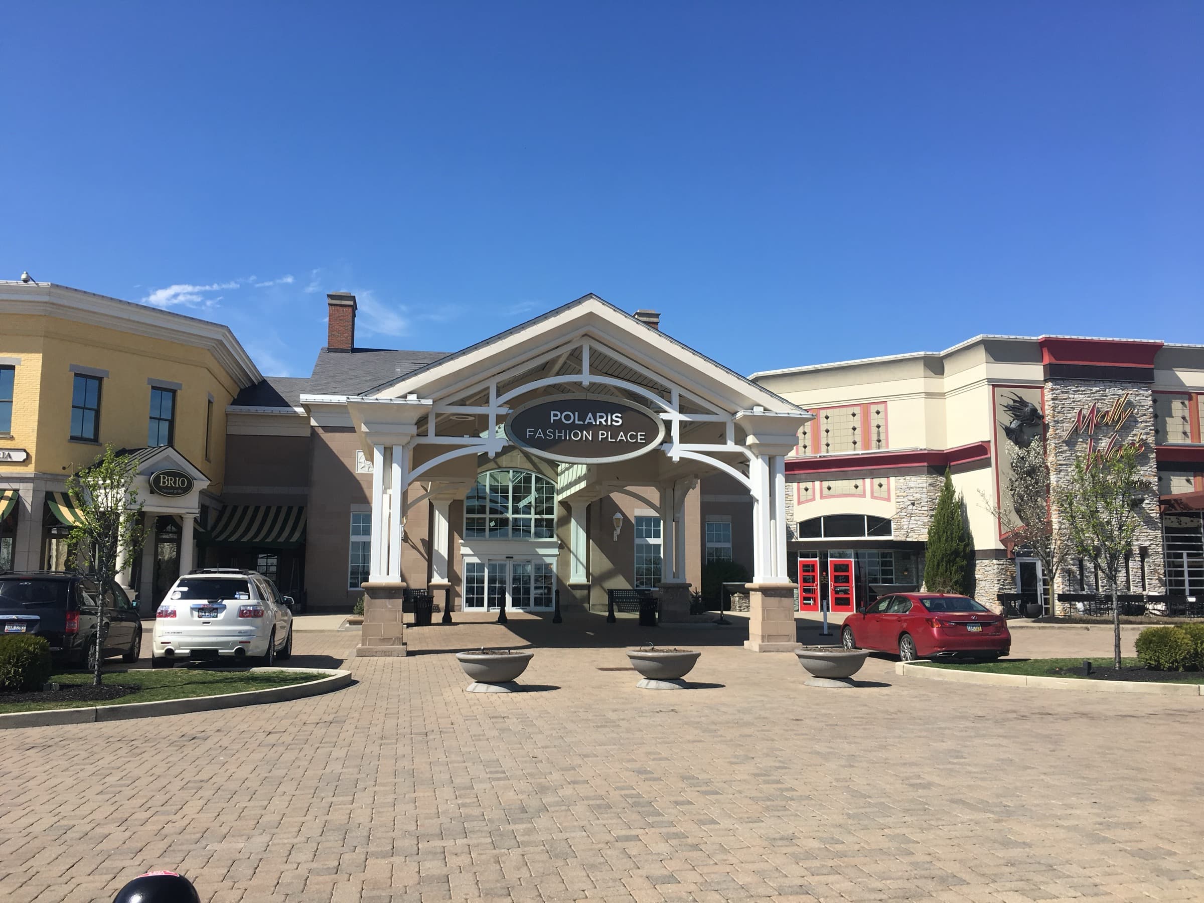 Sunlit main entrance of Polaris Fashion Place under a clear blue sky